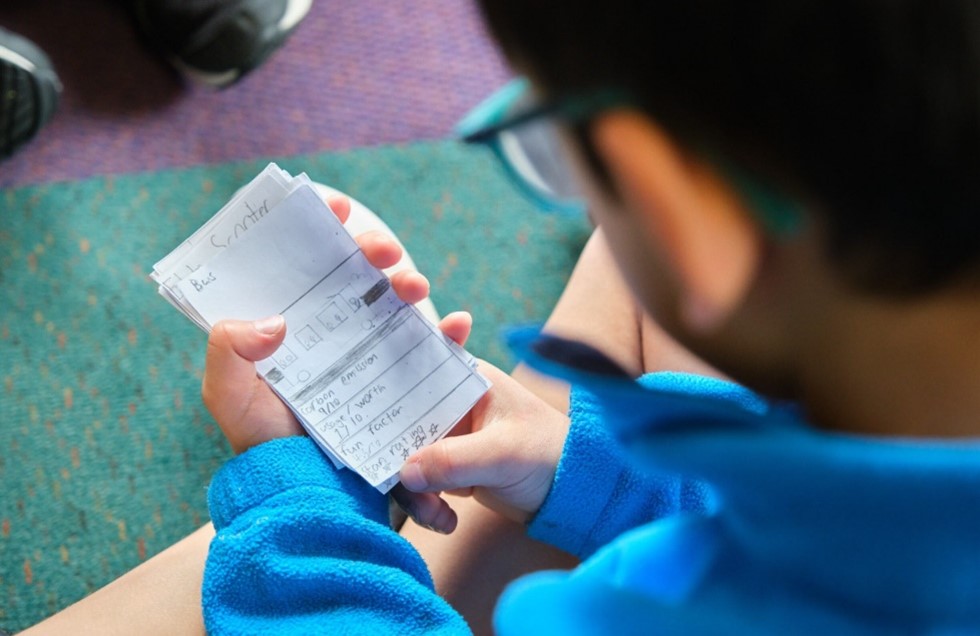 A student looks at their handmade top trumps cards