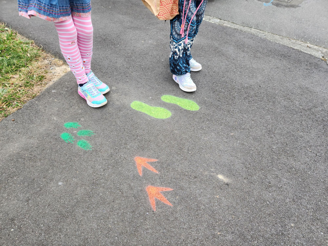 A walking school bus follows footsteps painted on the ground
